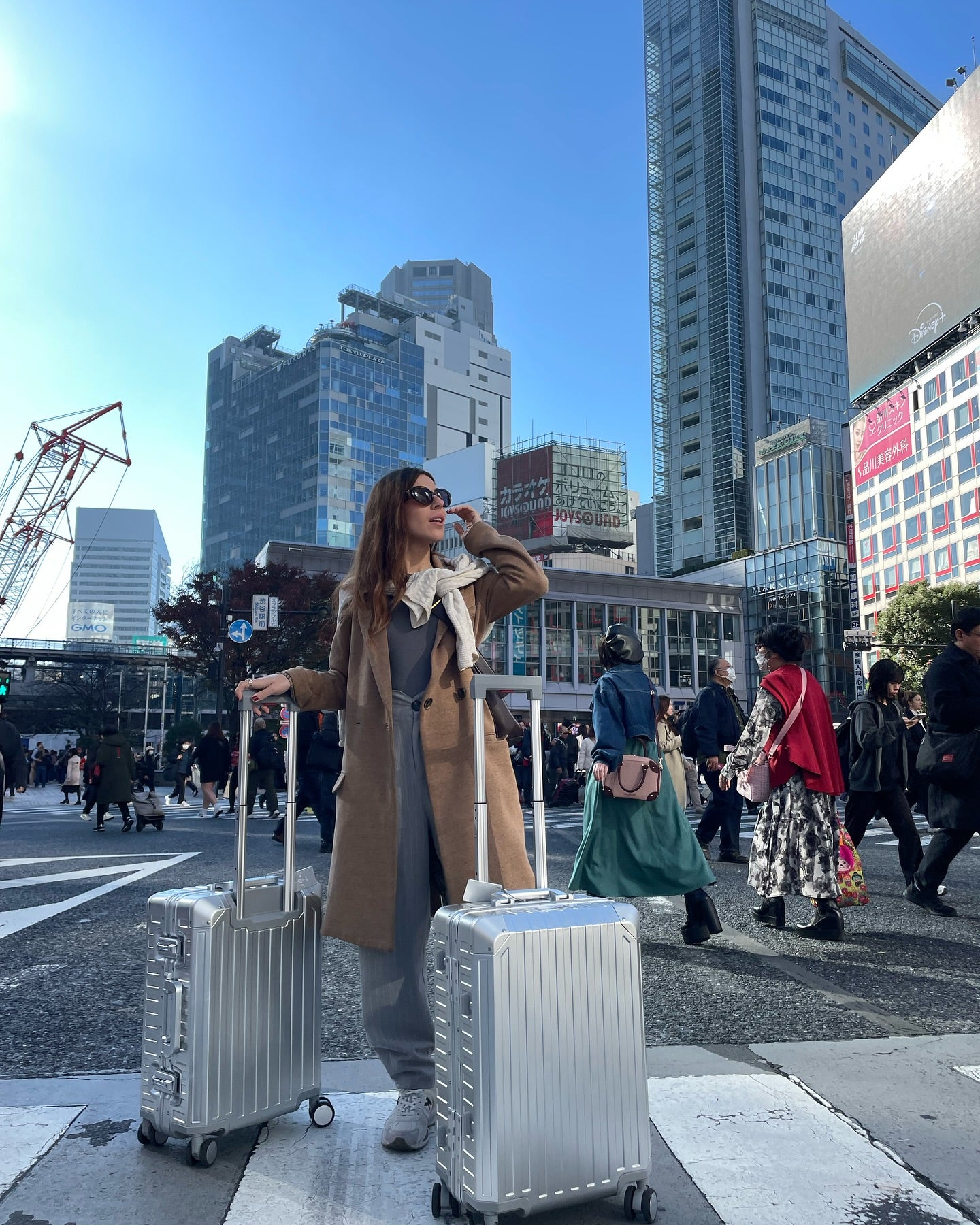 Silver aluminum suitcases with sleek hard shell design, spinner wheels, and telescopic handles, set in a busy urban crosswalk, ideal for luxury and business travel.